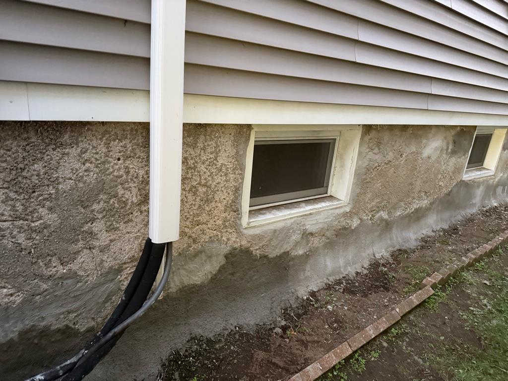 Foundation wall after re-pointing repair in Stratford CT with sealed cracks and restored cement around basement window